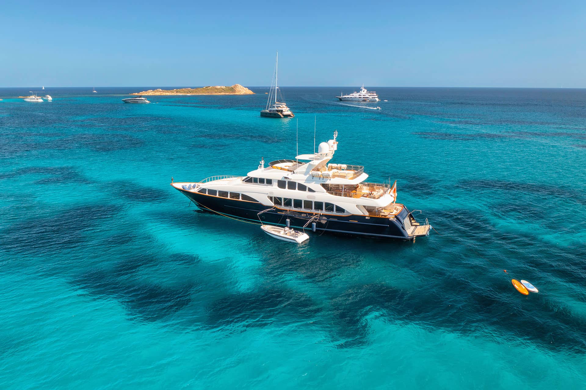 Aerial view of a luxury yacht cruising on clear blue sea under sunny skies